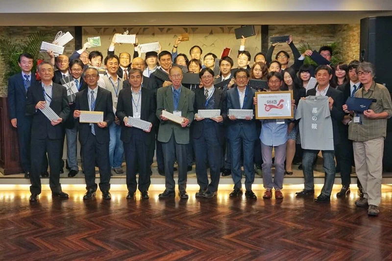 HHKB誕生20周年記念パーティーの時の集合写真。前列右から3人目の方が持っているのは、20周年に合わせて外部デザイナーに発注した記念ロゴ。